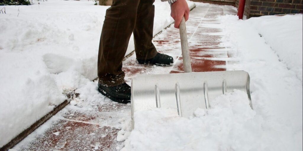 using a snow shovel on a sidewalk