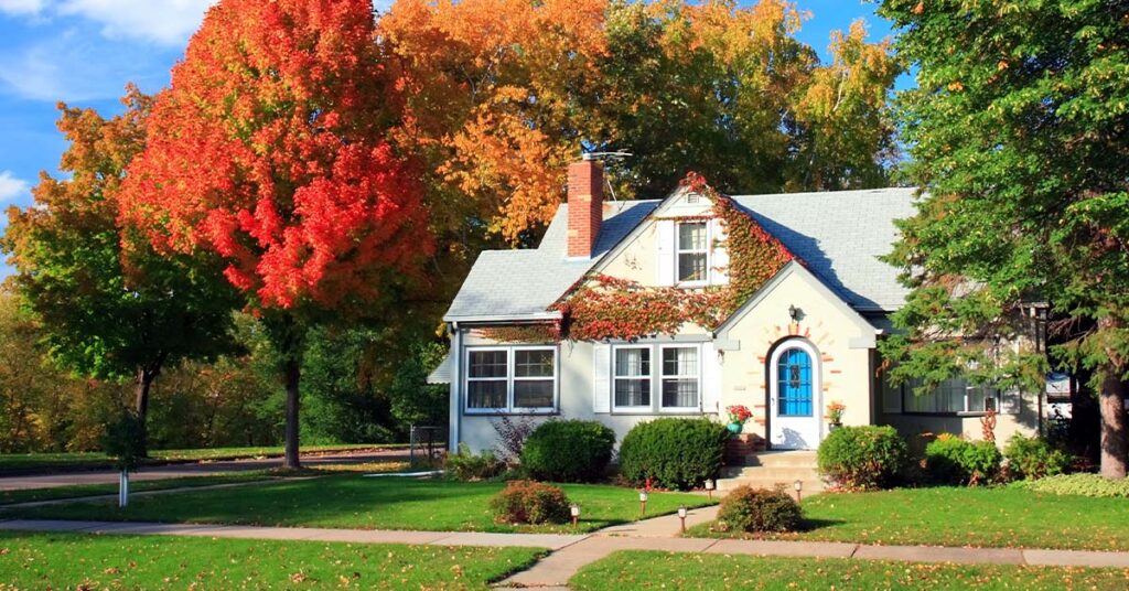 Image of a house in the fall surrounded by changing trees