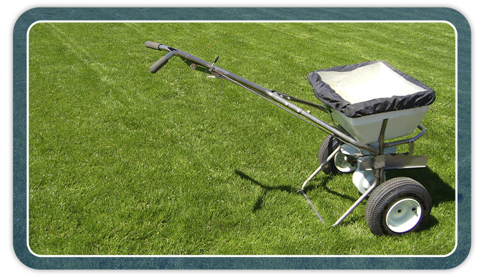Image of a fertilizer spreader on a grass lawn.