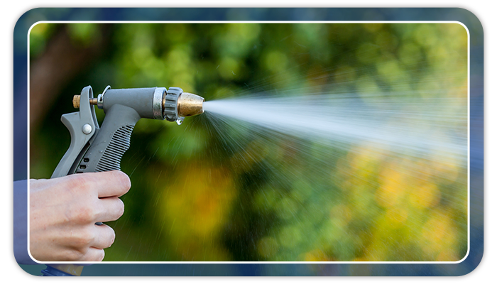 Image of a hand holding a garden hose that is spraying water.